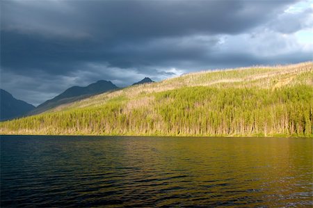 simsearch:400-05705152,k - Sunlight illuminates the shoreline of Kintla Lake against a stormy sky in Glacier National Park - USA. Stock Photo - Budget Royalty-Free & Subscription, Code: 400-04924987