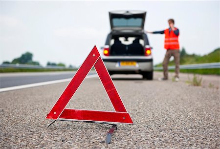 Warning tiangle behind a broken down car with a motorist calling for assistance. Focus on the triangle Stock Photo - Budget Royalty-Free & Subscription, Code: 400-04922254