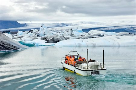 An amphibuous vehicle taking tourists for a cruise around the icebergs in the Jokulsarlon glacier lake, where huge chunks of ice from the Vatnajokull glacier float out to the Atlantic ocean Stock Photo - Budget Royalty-Free & Subscription, Code: 400-04923192