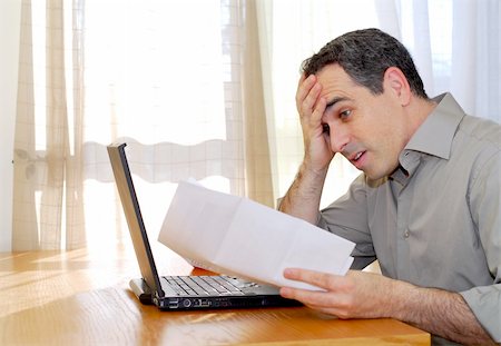 Man sitting at a desk looking at bills with horror Foto de stock - Super Valor sin royalties y Suscripción, Código: 400-04940479