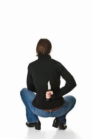 Young woman wearing blue jeans and a black jacket crouches and holds a knife behind her back. Isolated on a white background. Stock Photo - Budget Royalty-Free & Subscription, Code: 400-05004189