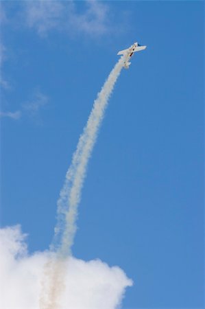 An aerobatic airplane trailing smoke flies up in smooth arc into a bright blue sky Stock Photo - Budget Royalty-Free & Subscription, Code: 400-05016636