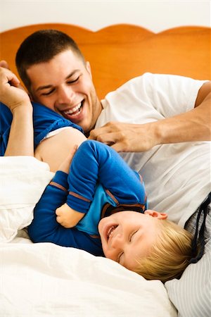 Caucasian toddler boy and father playing and tickling in bed. Stock Photo - Budget Royalty-Free & Subscription, Code: 400-05012535