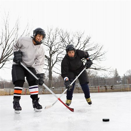 Two boys in ice hockey uniforms playing hockey on ice rink. Stock Photo - Budget Royalty-Free & Subscription, Code: 400-05013485