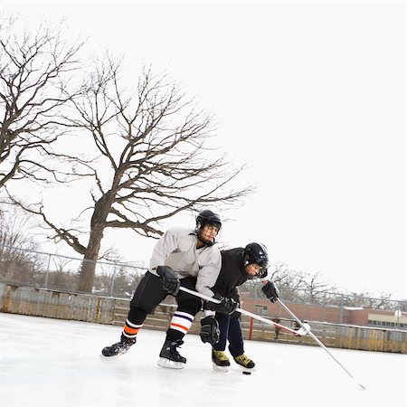 Two boys in ice hockey uniforms playing hockey on ice rink. Stock Photo - Budget Royalty-Free & Subscription, Code: 400-05013486