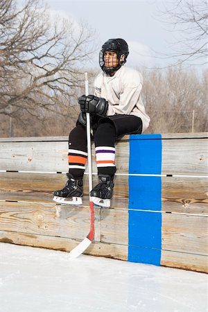 Boy in ice hockey uniform holding hockey stick sitting on sidelines. Stock Photo - Budget Royalty-Free & Subscription, Code: 400-05013487