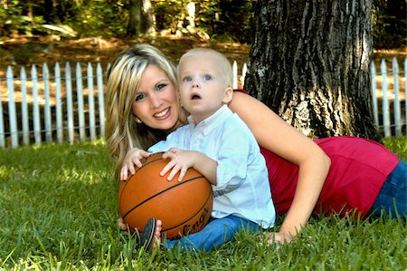 photo picket garden - young mother shares outdoor time with young son.  He is holding a basketball and is enthralled by his surroundings.  Both have on jeans.  Son has on white shirt and mom has on hot pink. Stock Photo - Budget Royalty-Free & Subscription, Code: 400-05025316