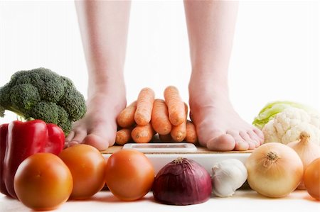 A pair of female feet standing on a bathroom scale with vegetables pilled around. Stock Photo - Budget Royalty-Free & Subscription, Code: 400-05029049