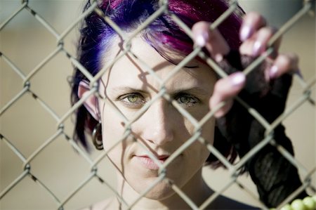 simsearch:400-04016564,k - Young woman with colorful hair behind a chain link fence Stock Photo - Budget Royalty-Free & Subscription, Code: 400-05054576