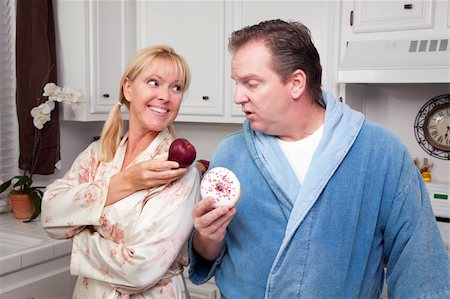 simsearch:400-05106591,k - Couple in Kitchen Eating Donut and Coffee or Healthy Fruit. Stock Photo - Budget Royalty-Free & Subscription, Code: 400-05106584
