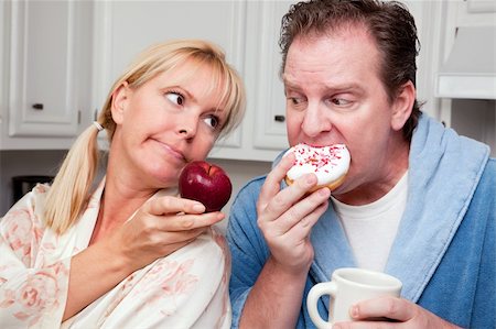 simsearch:400-05106591,k - Couple in Kitchen Eating Donut and Coffee or Healthy Fruit. Stock Photo - Budget Royalty-Free & Subscription, Code: 400-05106587