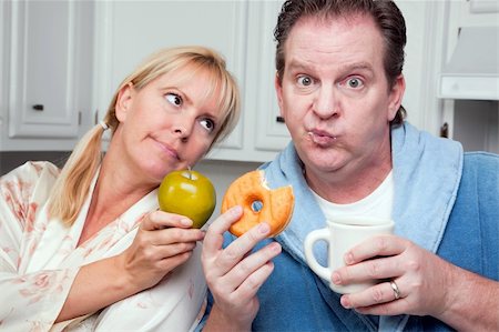 simsearch:400-05106591,k - Couple in Kitchen Eating Donut and Coffee or Healthy Fruit. Stock Photo - Budget Royalty-Free & Subscription, Code: 400-05106588