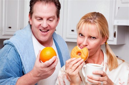 simsearch:400-05106591,k - Couple in Kitchen Eating Donut and Coffee or Healthy Fruit. Stock Photo - Budget Royalty-Free & Subscription, Code: 400-05106595