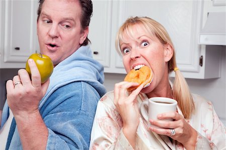 simsearch:400-05106591,k - Couple in Kitchen Eating Donut and Coffee or Healthy Fruit. Stock Photo - Budget Royalty-Free & Subscription, Code: 400-05106596
