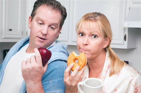 simsearch:400-05106591,k - Couple in Kitchen Eating Donut and Coffee or Healthy Fruit. Stock Photo - Budget Royalty-Free & Subscription, Code: 400-05106590