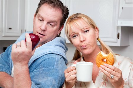 simsearch:400-05106591,k - Couple in Kitchen Eating Donut and Coffee or Healthy Fruit. Stock Photo - Budget Royalty-Free & Subscription, Code: 400-05106591