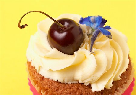 simsearch:400-04764403,k - Miniature vanilla cupcake with icing, fresh cherry and blue flower on yellow background Stock Photo - Budget Royalty-Free & Subscription, Code: 400-05125458