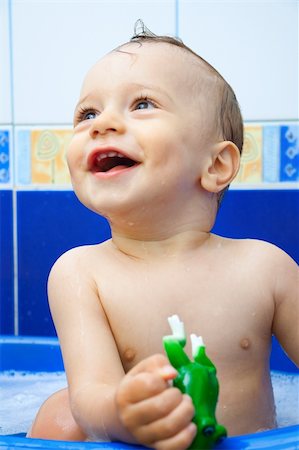 child bathes and holds in a hand a green toy-frog Stock Photo - Budget Royalty-Free & Subscription, Code: 400-05125510