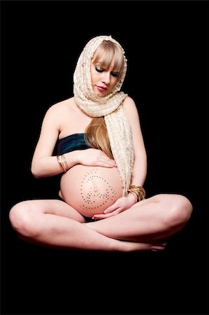 pregnancy nude - Beautiful pregnant Caucasian woman with head scarf sitting in lotus position holding naked belly covered with rhinestones, isolated Stock Photo - Budget Royalty-Free & Subscription, Code: 400-05133874