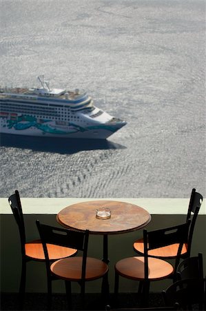 simsearch:649-02054287,k - View across a balcony with table and chairs, looking down over the caldera in Santorini, where a cruise ship has arrived Stock Photo - Budget Royalty-Free & Subscription, Code: 400-05144118