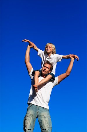 family fun day background - Father giving his son a piggyback ride against the blue sky Foto de stock - Super Valor sin royalties y Suscripción, Código: 400-05145020