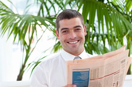 Smiling attractive businessman reading a newspaper in workplace Stock Photo - Budget Royalty-Free & Subscription, Code: 400-05179442