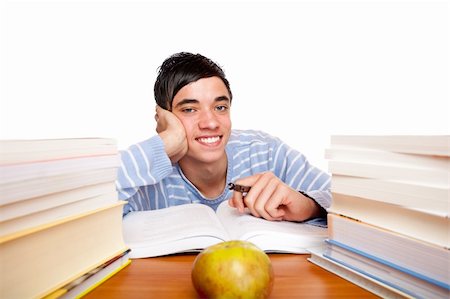 simsearch:400-04505681,k - Young handsome student smiles happy and sits between study books at desk. Isolated on white. Stock Photo - Budget Royalty-Free & Subscription, Code: 400-05195695