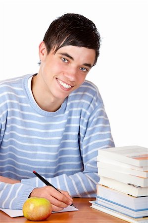 simsearch:400-04505681,k - Young student is sitting on desk with study books and learns for his exams. He smiles happy into camera. Isolated on white. Stock Photo - Budget Royalty-Free & Subscription, Code: 400-05196627
