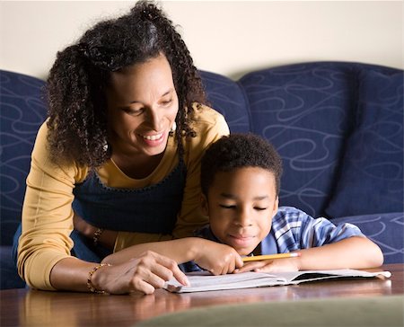 A mid adult African American woman sits on a couch while helping her young some with his homework. Horizontal shot. Stock Photo - Budget Royalty-Free & Subscription, Code: 400-05198666
