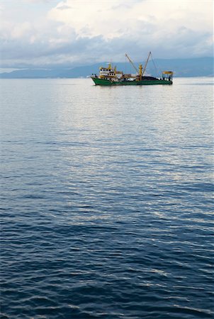 Single small fishing trawler leaving the harbor into the the blue Aegean sea to go fishing on a cloudy winter's day. Stock Photo - Budget Royalty-Free & Subscription, Code: 400-05205191