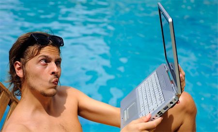 Man looks into his webcam while sitting poolside Stock Photo - Budget Royalty-Free & Subscription, Code: 400-05209356