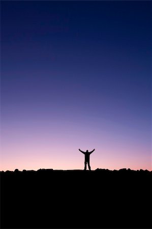 silhouette of man standing in a mountain top - Silhouette of a man raising his hands into the sunrise after conquering a summit Stock Photo - Budget Royalty-Free & Subscription, Code: 400-05222745
