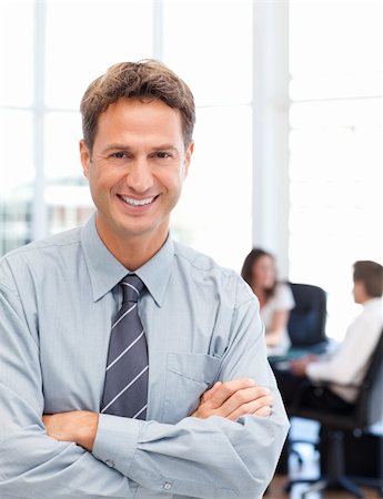 simsearch:400-05746962,k - Happy businessman standing in front of his team while working at a table in the background Stock Photo - Budget Royalty-Free & Subscription, Code: 400-05298014
