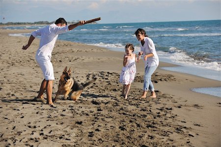 simsearch:400-05309800,k - happy young family in white clothing have fun and play with beautiful dog at vacations on beautiful beach Stock Photo - Budget Royalty-Free & Subscription, Code: 400-05291374
