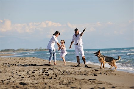 simsearch:400-05309800,k - happy young family in white clothing have fun and play with beautiful dog at vacations on beautiful beach Stock Photo - Budget Royalty-Free & Subscription, Code: 400-05291376