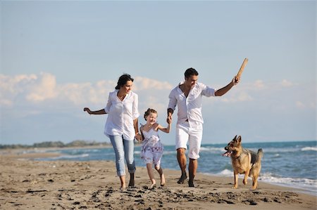 simsearch:400-05309800,k - happy young family in white clothing have fun and play with beautiful dog at vacations on beautiful beach Stock Photo - Budget Royalty-Free & Subscription, Code: 400-05291380