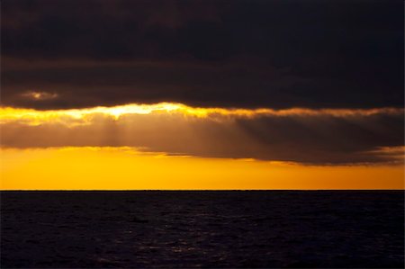 simsearch:400-07748817,k - The sun rises behind storm clouds on the ocean Stock Photo - Budget Royalty-Free & Subscription, Code: 400-05293129