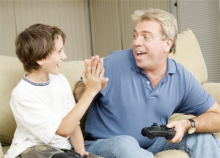 simsearch:400-05751526,k - Uncle giving his nephew a high five as they play video games.  Could also be father and son. Stock Photo - Budget Royalty-Free & Subscription, Code: 400-05315414