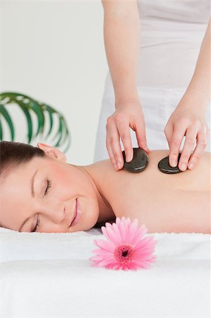 simsearch:400-05352124,k - Happy young woman having a hot stone massage and a pink gerbera Stock Photo - Budget Royalty-Free & Subscription, Code: 400-05340031