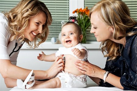 Beautiful female doctor examining little smiling baby girl, held by mother Stock Photo - Budget Royalty-Free & Subscription, Code: 400-05356155