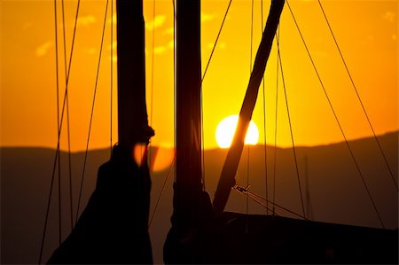 simsearch:400-07748817,k - Golden sunset and sailboats - ropes, sail and sun behind the mountain Stock Photo - Budget Royalty-Free & Subscription, Code: 400-05351540