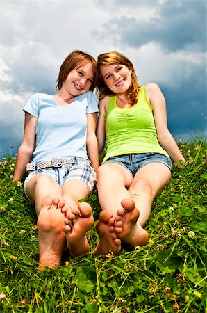 Two young teenage girl friends sitting barefoot on summer meadow Photographie de stock - Aubaine LD & Abonnement, Code: 400-05372366