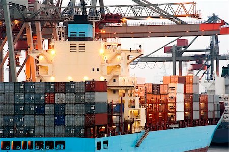 A huge container ship being unloaded at dawn in an industrial harbor by overhead cranes Stock Photo - Budget Royalty-Free & Subscription, Code: 400-05382654