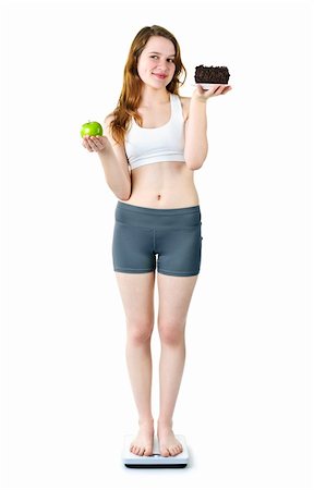simsearch:400-05106591,k - Tempted young woman holding apple and chocolate cake standing on scale Stock Photo - Budget Royalty-Free & Subscription, Code: 400-05383437