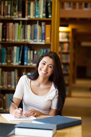 Portrait of a smiling student writing a paper in the library Foto de stock - Super Valor sin royalties y Suscripción, Código: 400-05668897