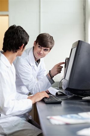 Scientist pointing at something on a monitor to his colleague in a laboratory Stock Photo - Budget Royalty-Free & Subscription, Code: 400-05669798