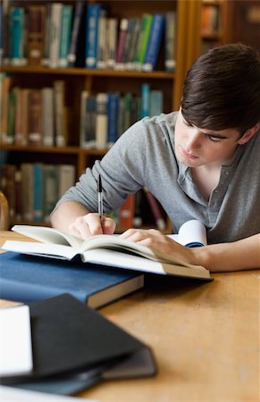 simsearch:400-05669803,k - Portrait of a handsome student writing an essay in a library Stock Photo - Budget Royalty-Free & Subscription, Code: 400-05669993