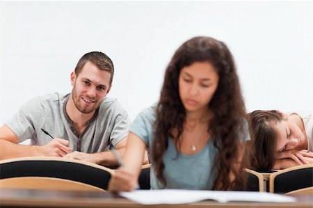 simsearch:400-05677768,k - Smiling students writing while their classmate is sleeping in an amphitheater Stock Photo - Budget Royalty-Free & Subscription, Code: 400-05677822