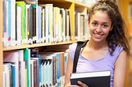 simsearch:400-05669803,k - Smiling female student posing with a book in a library Stock Photo - Budget Royalty-Free & Subscription, Code: 400-05678133