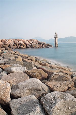 simsearch:400-04272525,k - Lighthouse on a Rocky Breakwall: A small lighthouse warns of a rough shoreline. Stock Photo - Budget Royalty-Free & Subscription, Code: 400-05679082